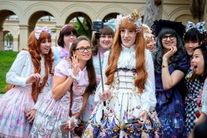 Group of white women dressed in a variety of Lolita styles take a picture together with a selfie-stick.