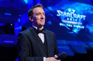 A picture of Paul Chaloner in a suit, looking proud. Behind him is a screen that says "STARCRAFT."