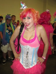 Image of a woman dressed up in pink at Bronycon. She has bright red hair and is smiling.