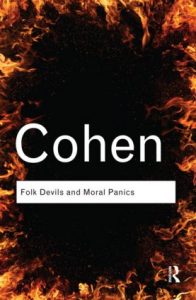 A picture of Stanley Cohen's book Folk Devils and Moral Panics with flames around the cover and black in the middle with the title and author's name.