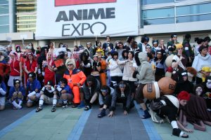 A large group of people wearing costumes in front of a sign for Anime Expo