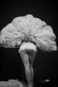 Burlesque performer facing backwards, feather fan
