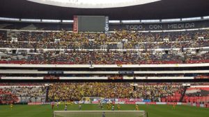 Home hooligans wearing yellow fill the seats behind their goal to root for their team in the Mexican League at Estadio Azteca