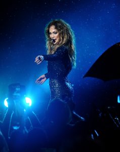Pop star Jennifer Lopez stands on stage and points into the crowd.