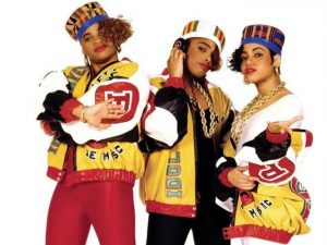 Three young women in very similar, brightly colored outfits pose in front of white background
