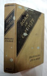 A tan book with a black diagnol section in the top left corner. The text on the spine and cover both reads, "Born in Captivity. Barbara Starke"