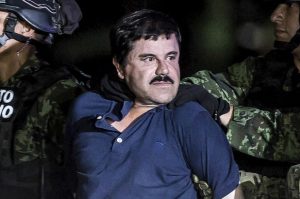 Arresting of a man known as "El Chapo" who is dressed in a blue shirt and being taken away by men in uniform. 