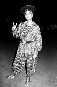 Woman standing, making a "peace sign" with one hand